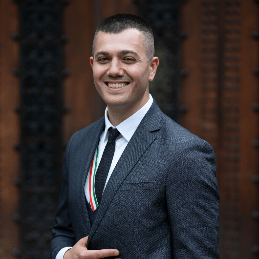 Couleurbursche_0620_Darmstadt_07_web-fs8 Burak Sahin, lächend, mit der Hand zwischen Brust und Bauch in einem Anzug